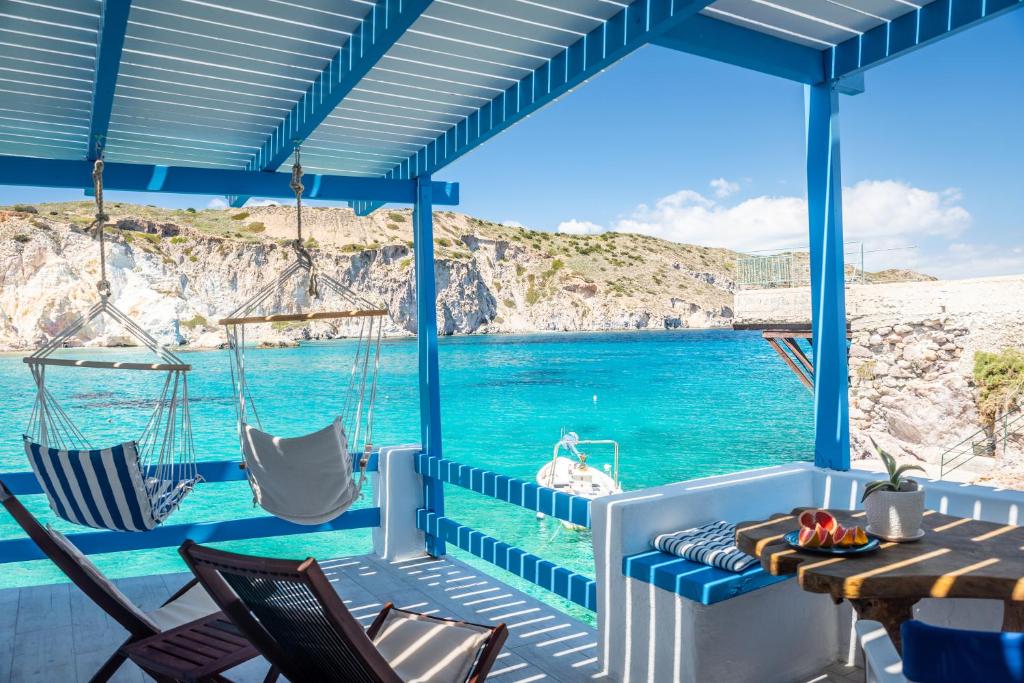 un porche con vistas al agua y a un barco en Aquanis Anchored, sea front house, Firopotamos, en Firopótamos