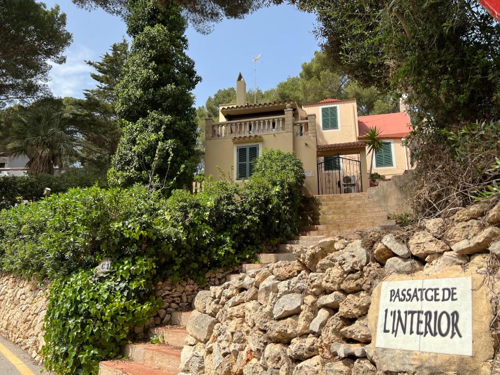 a house with a sign in front of a stone wall at Casa Montse in Cala Galdana