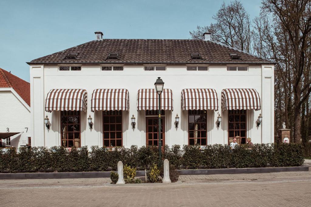 une grande maison blanche avec des auvents. dans l'établissement Boutique Hotel Restaurant BAL, à Echteld