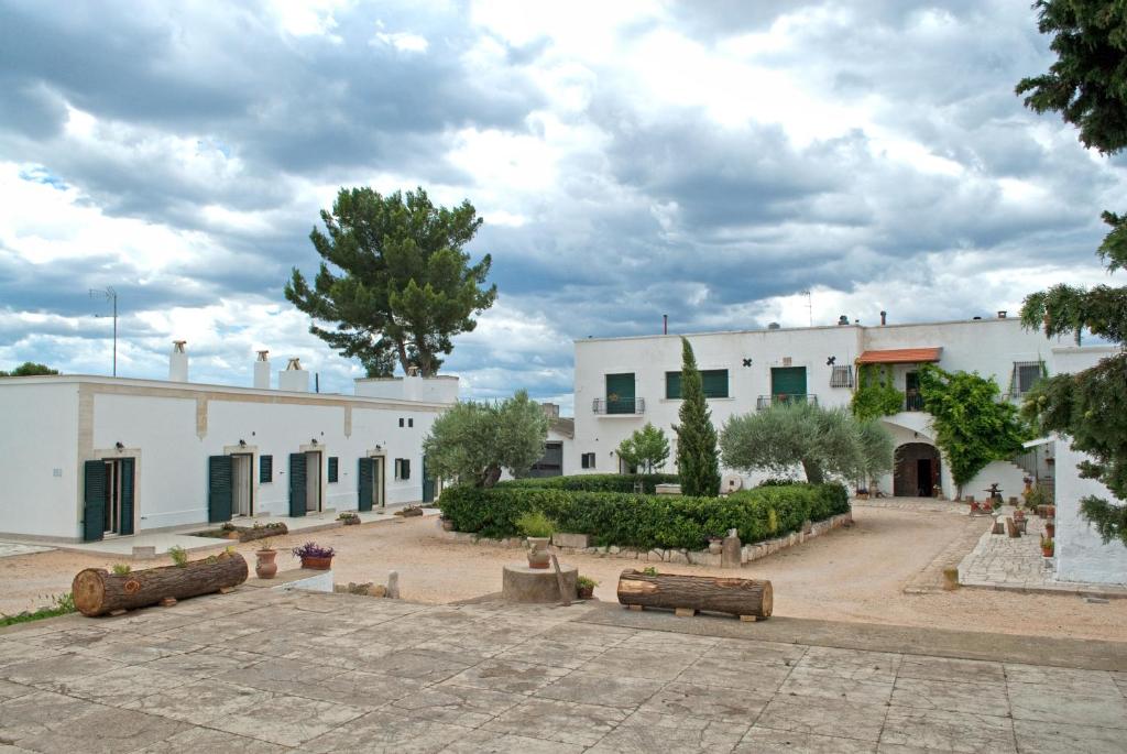a large white building with a courtyard and trees at Masseria Strada Agriturismo in Ginosa