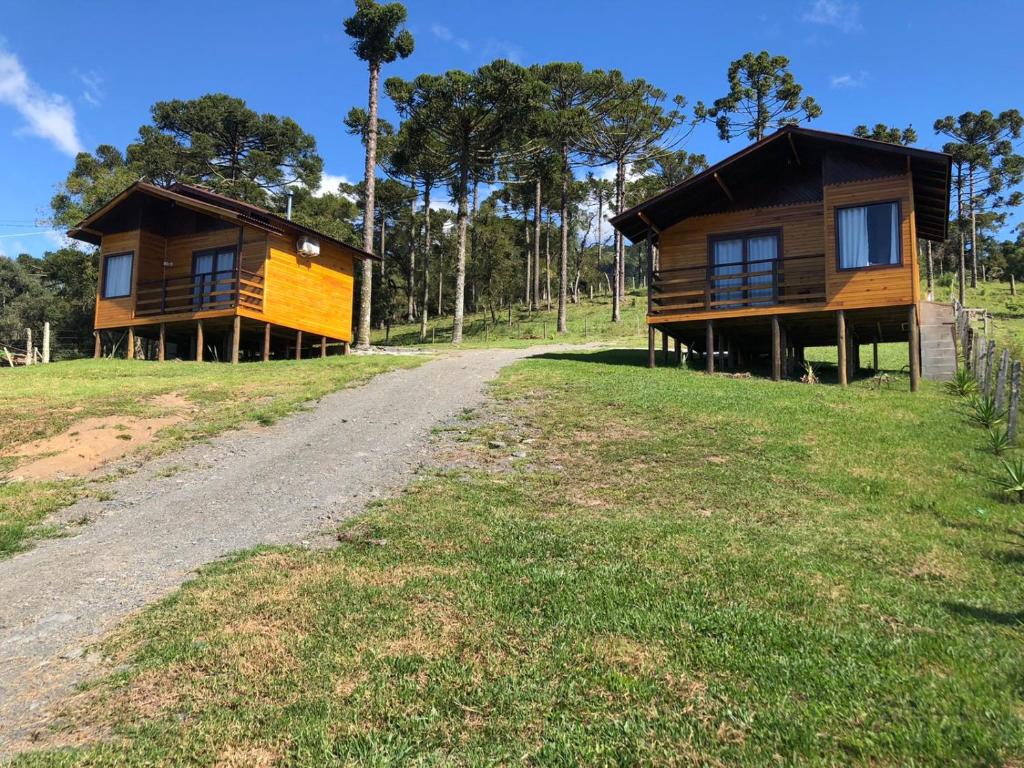 two houses on a hill with a dirt road at Hospedagem Família Cruz in Urubici