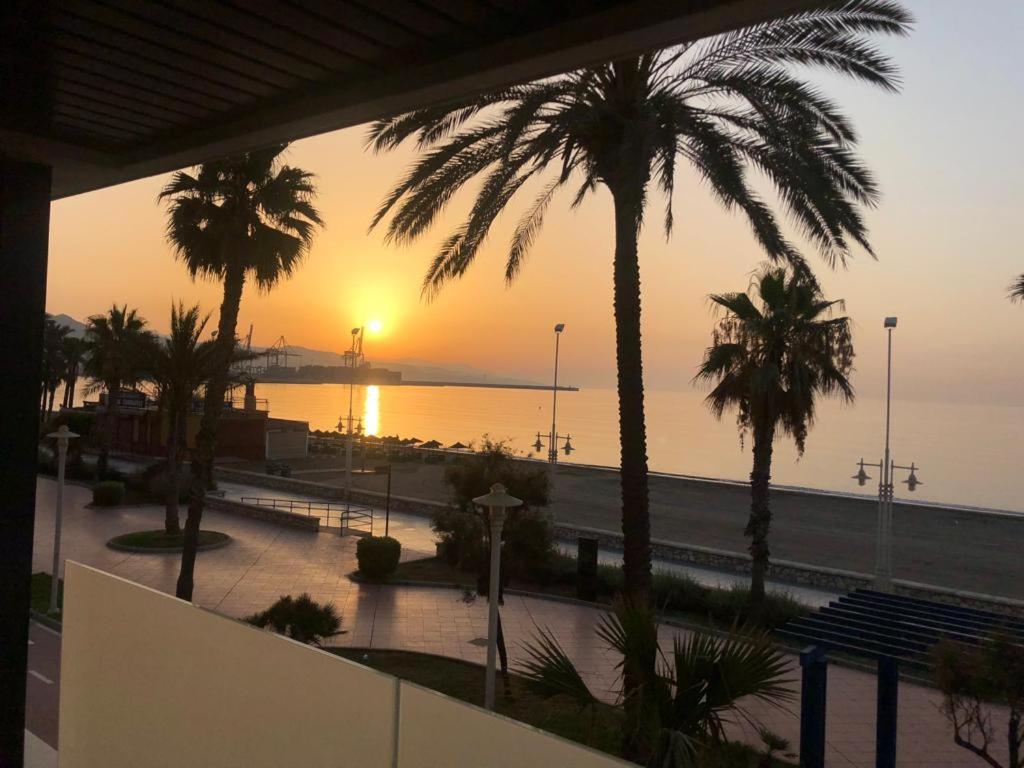 Málaga paraíso frente al mar في مالقة: اطلالة على شاطئ فيه نخل وغروب الشمس