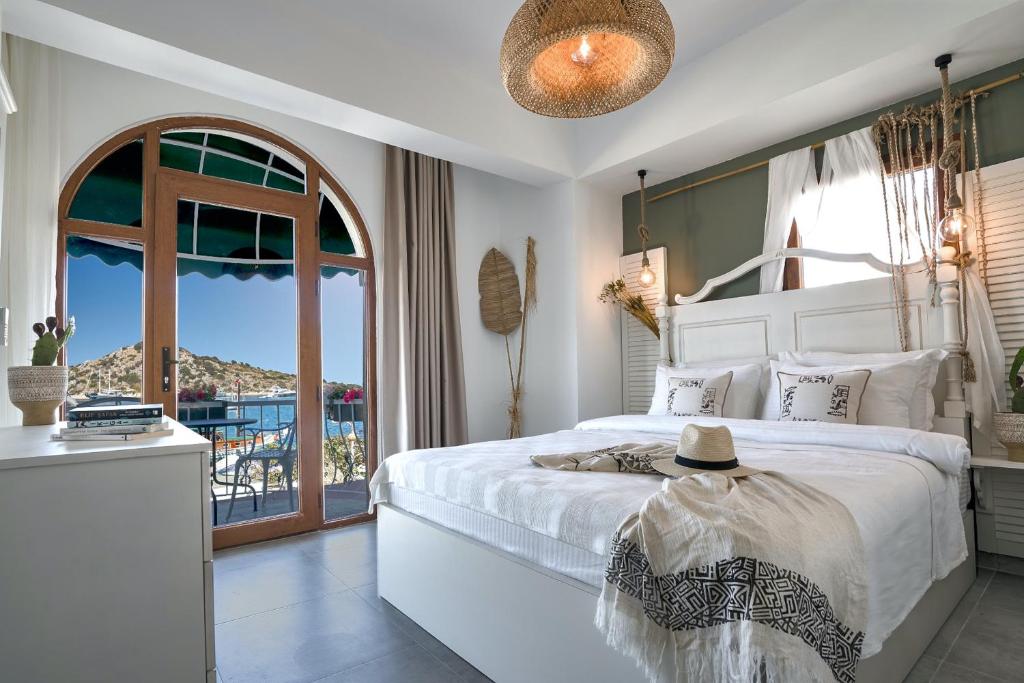 a bedroom with a white bed and a balcony at Liman Hotel Gümüslük - Adult Only in Bodrum City