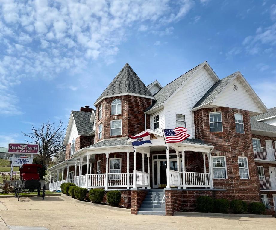 Una gran casa de ladrillo con una bandera americana. en Carriage House Inn, en Branson