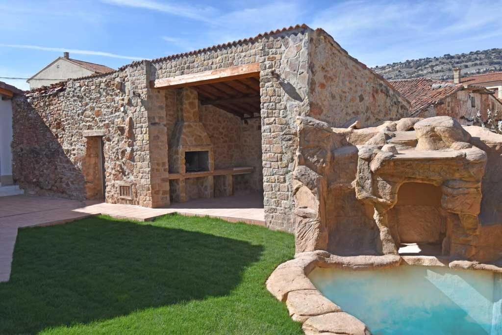 ein Steingebäude mit einem Pool im Hof in der Unterkunft Casa Rural La Cueva del Agua in Fuentetoba