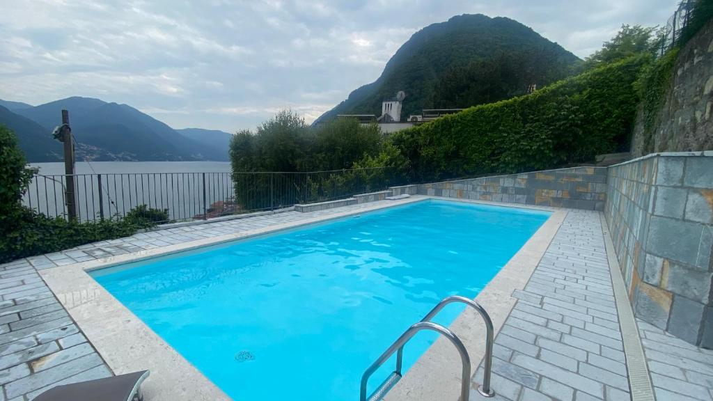 a large blue swimming pool with mountains in the background at Casa Mille Luci in Argegno
