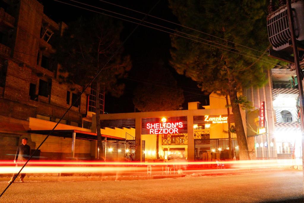 スワートにあるShelton Rezidor Swatの夜に生まれ変わる骨格を読む看板のある建物