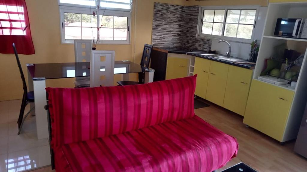 un soggiorno con divano rosso in cucina di Chez Claude ad Anse-Bertrand