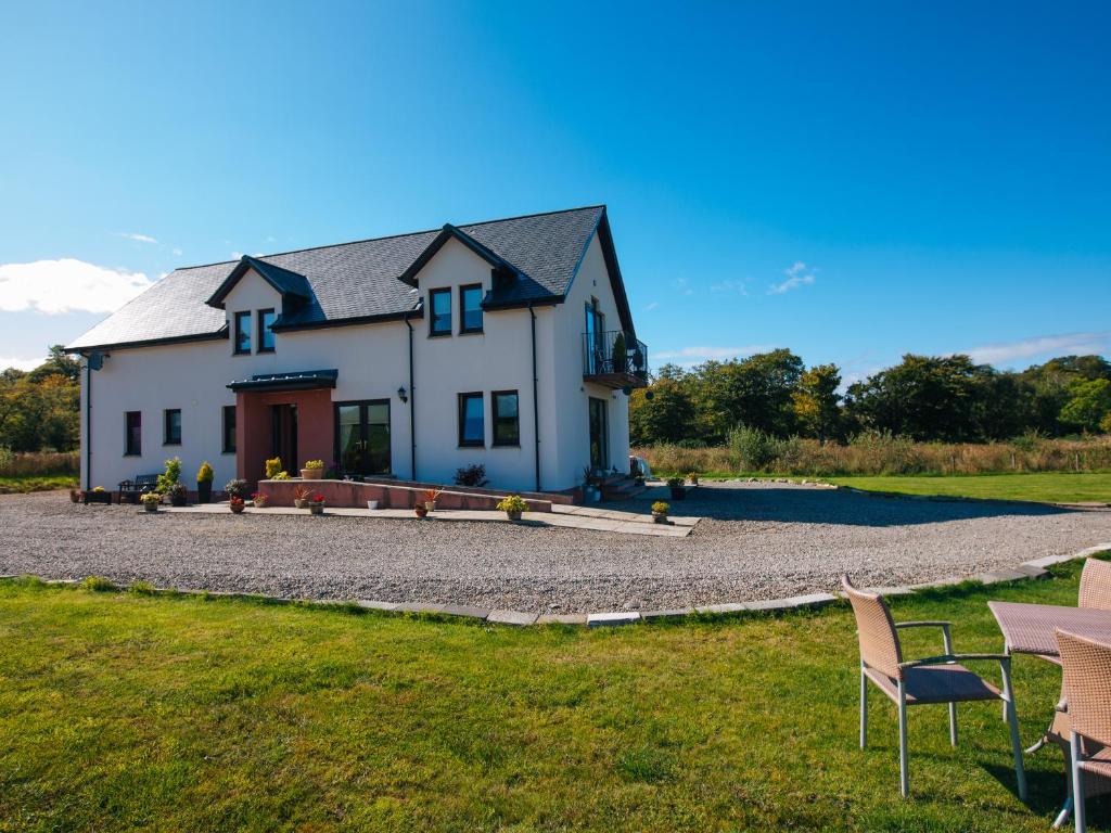 une grande maison blanche avec des chaises en face de celle-ci dans l'établissement Shenavallie Farm, à Benderloch