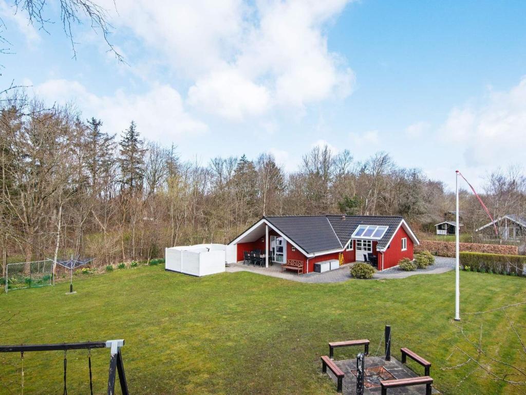 a red house in a field with a yard at 6 person holiday home in Hemmet in Falen