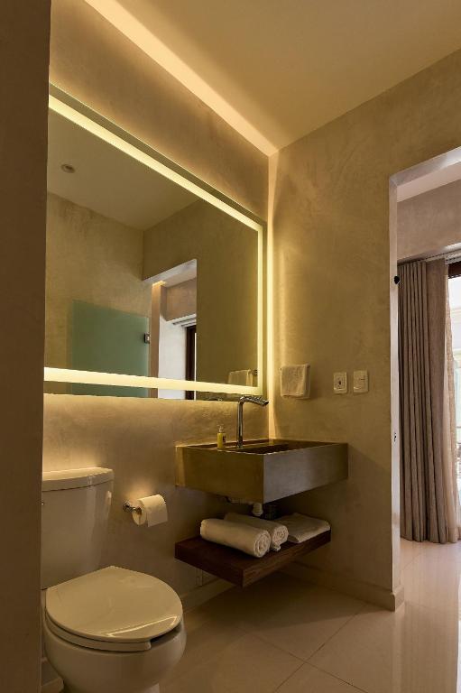 Un baño con lavabo, inodoro y espejo. en Casa Quiote Hotel Boutique City Center based - Adults Only, en Oaxaca City