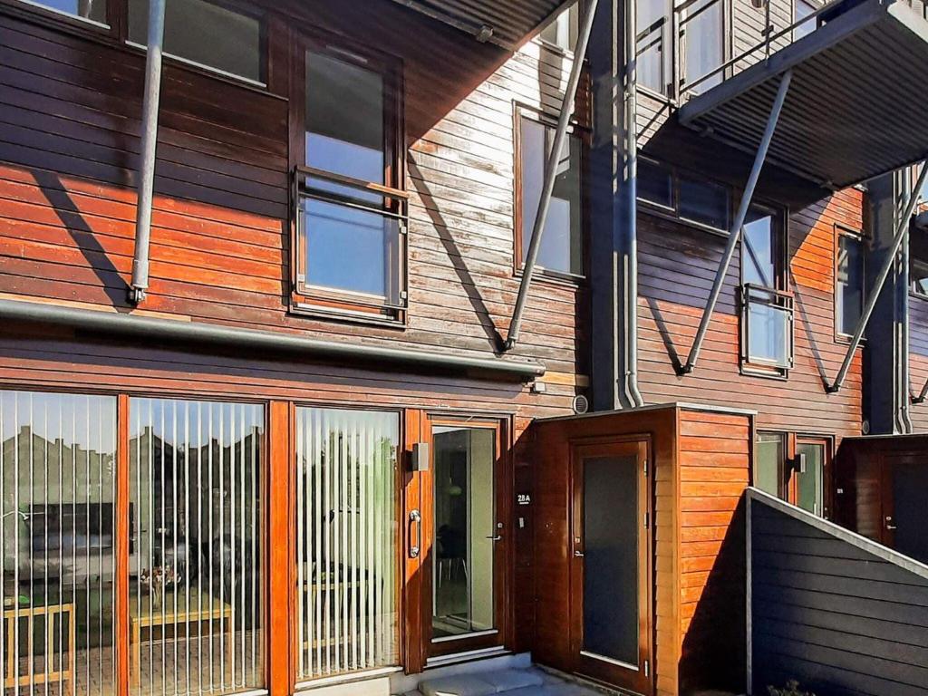 uma casa de madeira com uma porta de madeira e janelas de vidro em Apartment Bogense LXI em Bogense