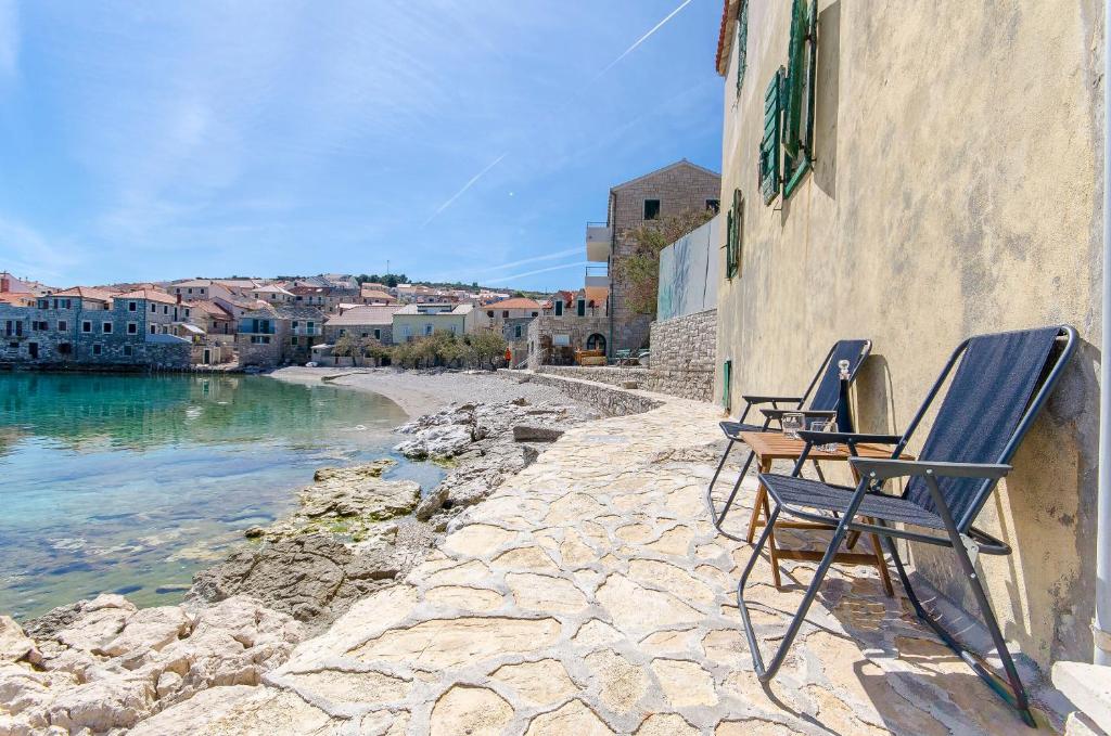 twee stoelen aan de zijkant van een gebouw naast het water bij Apartment Paradise in Postira