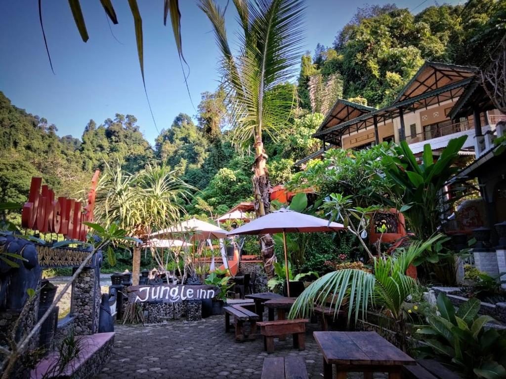 武吉拉旺的住宿－Jungle Inn Bukit lawang，一个带桌子和遮阳伞的庭院。