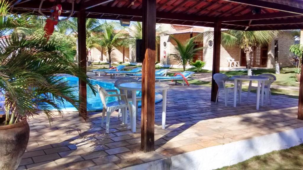 a patio with tables and chairs next to a pool at Pousada 7 Mares in Canoa Quebrada