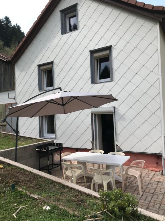 a table and chairs with an umbrella in front of a house at Le Gîte du Petit Béret in Plainfaing