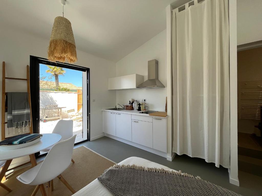 Una cocina y un comedor con mesa y sillas. en Maisonnette à proximité plage et port de St-Martin, en Saint-Martin-de-Ré