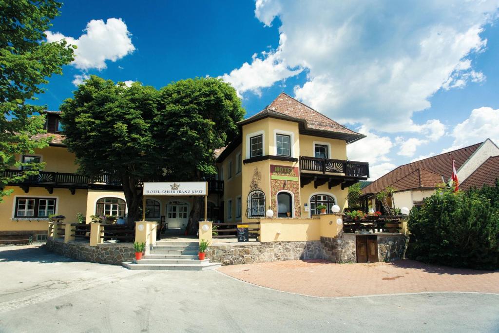 Rohr im Gebirge的住宿－Hotel Kaiser Franz Josef，一座黄色的大建筑,前面有一棵树