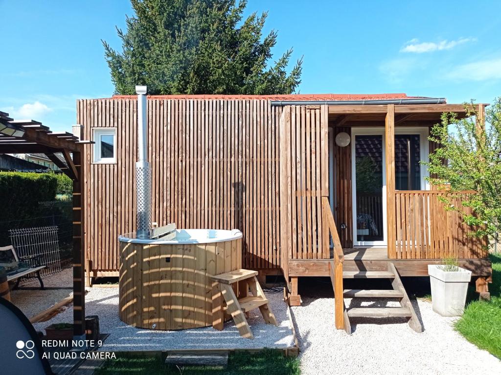 a small wooden cabin with a grill and a chair at le clos des genêts in Agencourt