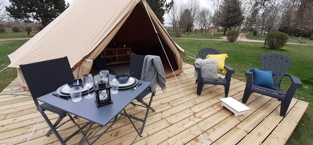 Tente Bell au camping Hautoreille في Bannes: خيمة على طاولة وكراسي على سطح السفينة