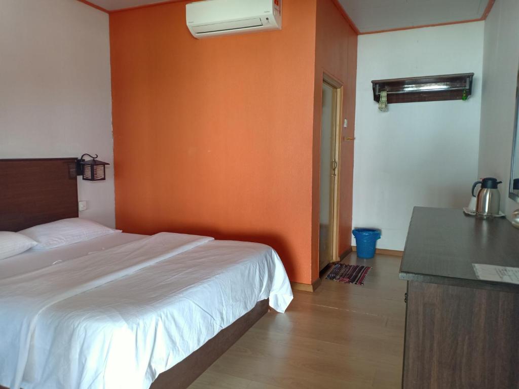 a bedroom with a bed and an orange wall at Suhaila Palace in Perhentian Islands