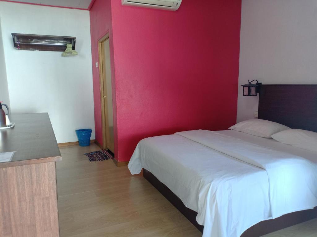 a bedroom with a white bed and a pink wall at Suhaila Palace in Perhentian Islands