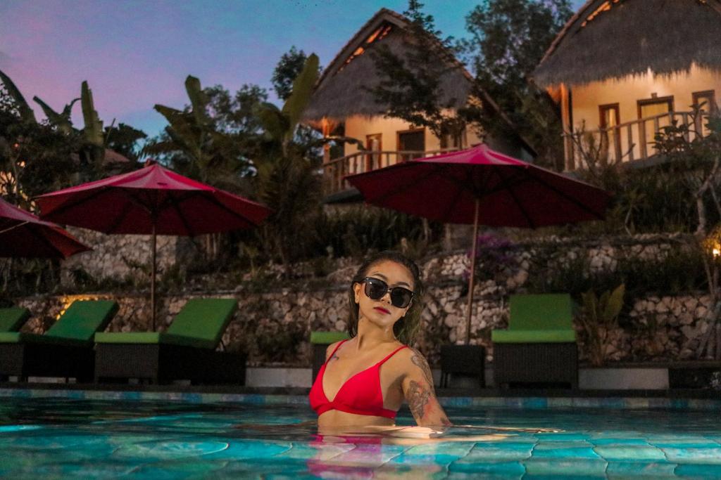 a woman in a swimming pool with umbrellas at NG Sweet Home in Nusa Penida