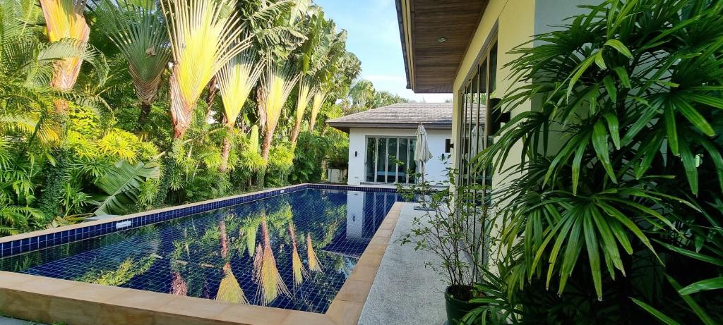 ein Pool vor einem Haus mit Palmen in der Unterkunft Beautiful villa walking distance from Bangtao Beach in Strand Bang Tao