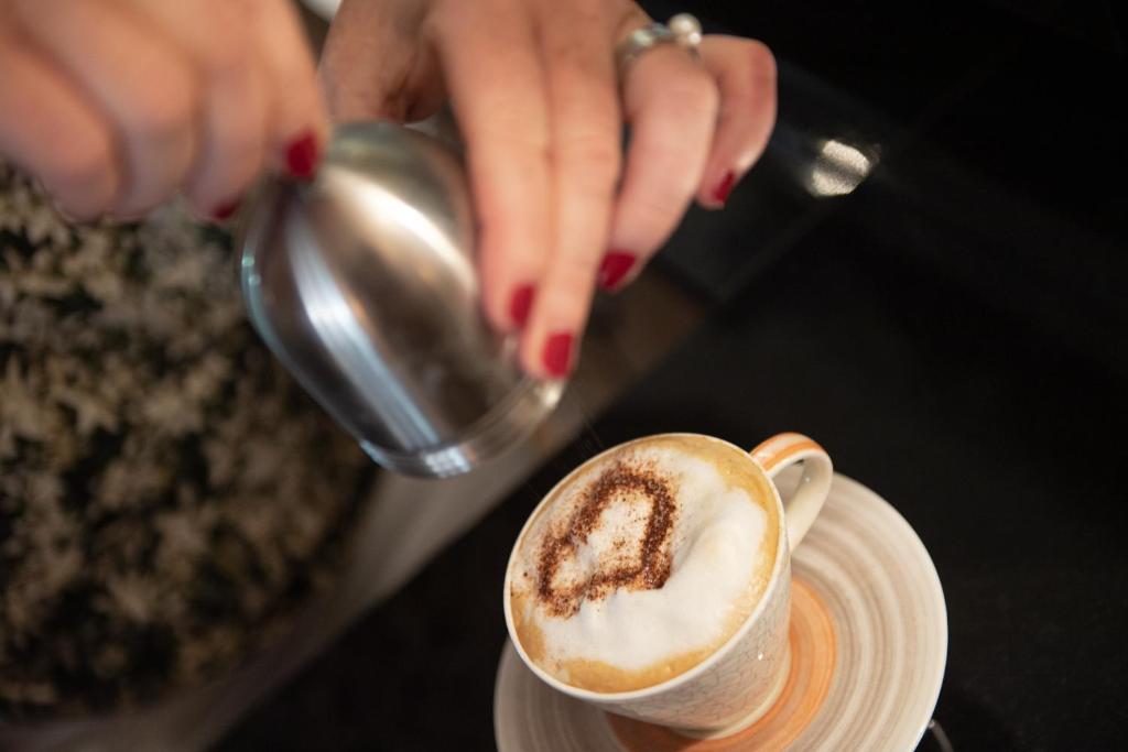 a woman pouring coffee into a cup on a plate at Matterhorn Lodge Boutique Hotel & Apartments in Zermatt