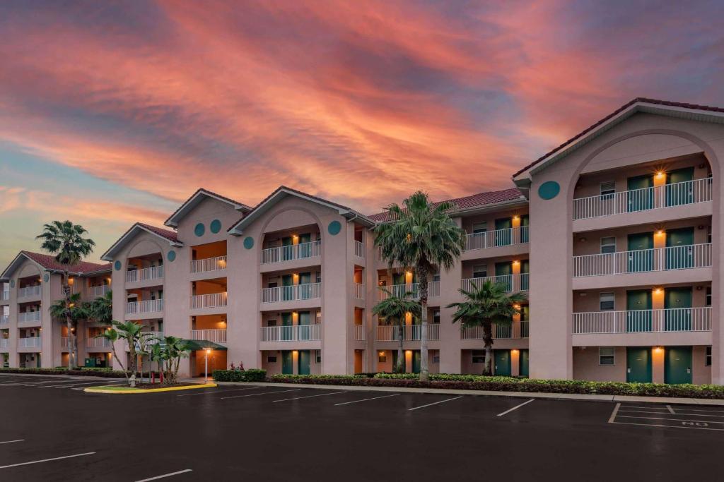 a large apartment building with palm trees in a parking lot at Vacation Villas 2, a Ramada by Wyndham in Kissimmee