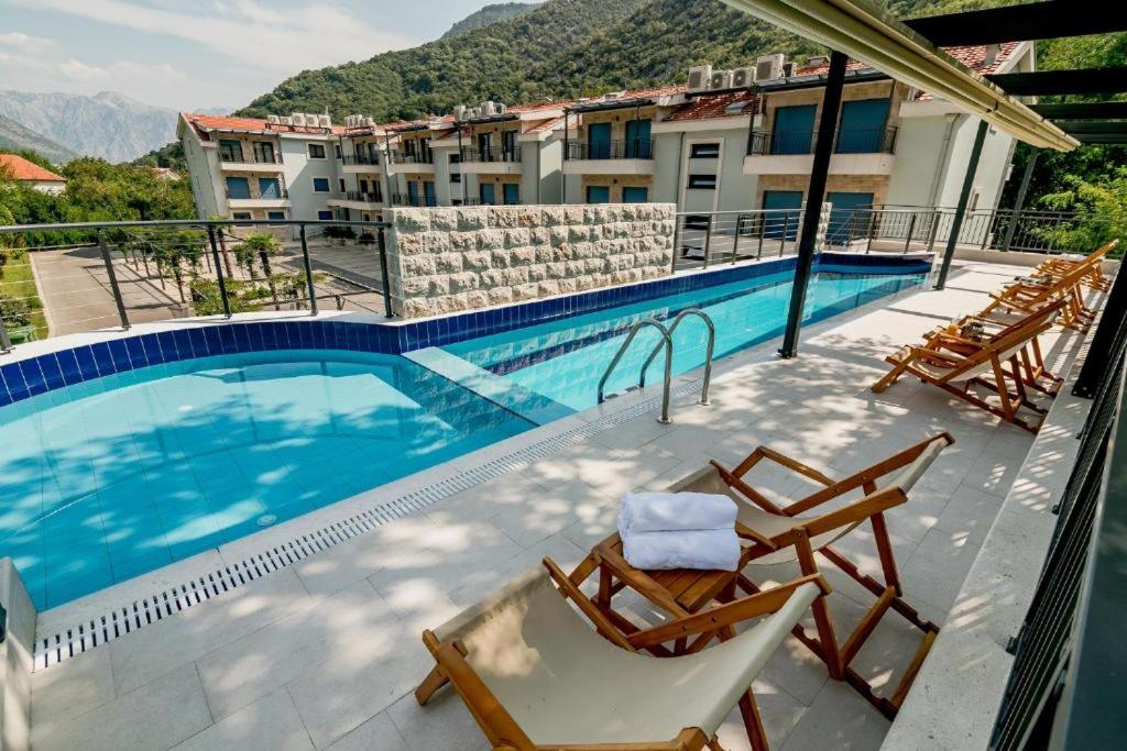 einen Balkon mit Stühlen und einem Pool in der Unterkunft Green Bay Apartments Morinj in Kotor