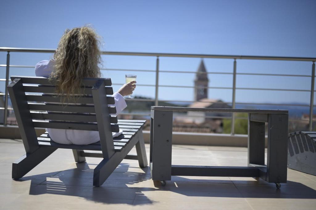 une femme assise sur un banc pour boire un verre dans l'établissement Guest House Adriatica by Pinch, à Pakoštane