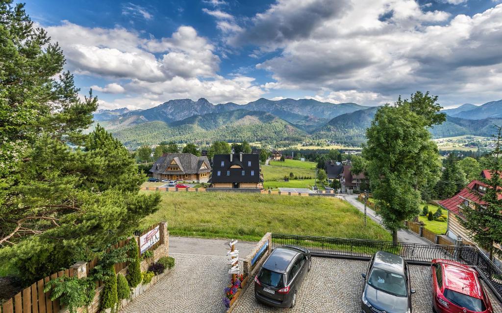 un grupo de coches estacionados en un estacionamiento con montañas en Apartamenty widokowe Cztery Pory Roku, en Kościelisko