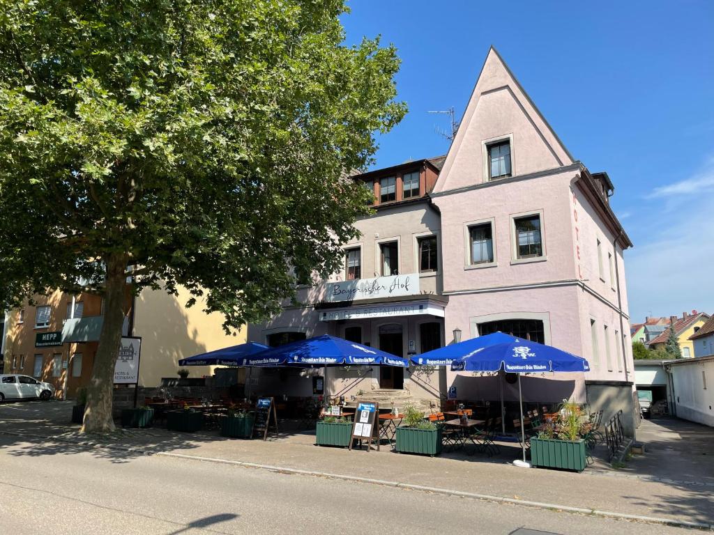 ein Gebäude mit Sonnenschirmen und Tischen davor in der Unterkunft Bayerischer Hof in Rothenburg ob der Tauber