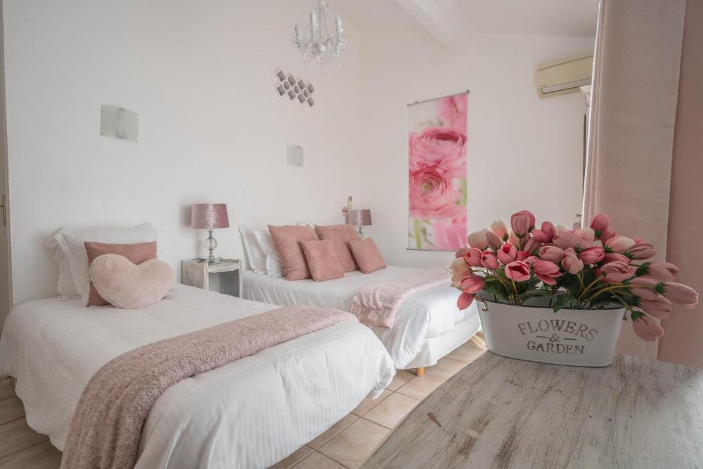 a bedroom with two beds and a vase of flowers at Hôtel Le Méditerranée in Hyères