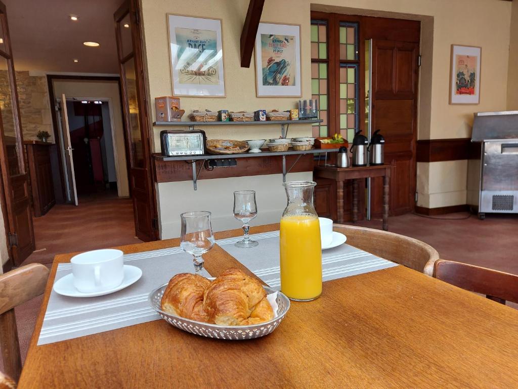 a table with a plate of croissants and a bottle of orange juice at Hotel de Normandie in Saint-Aubin-sur-Mer