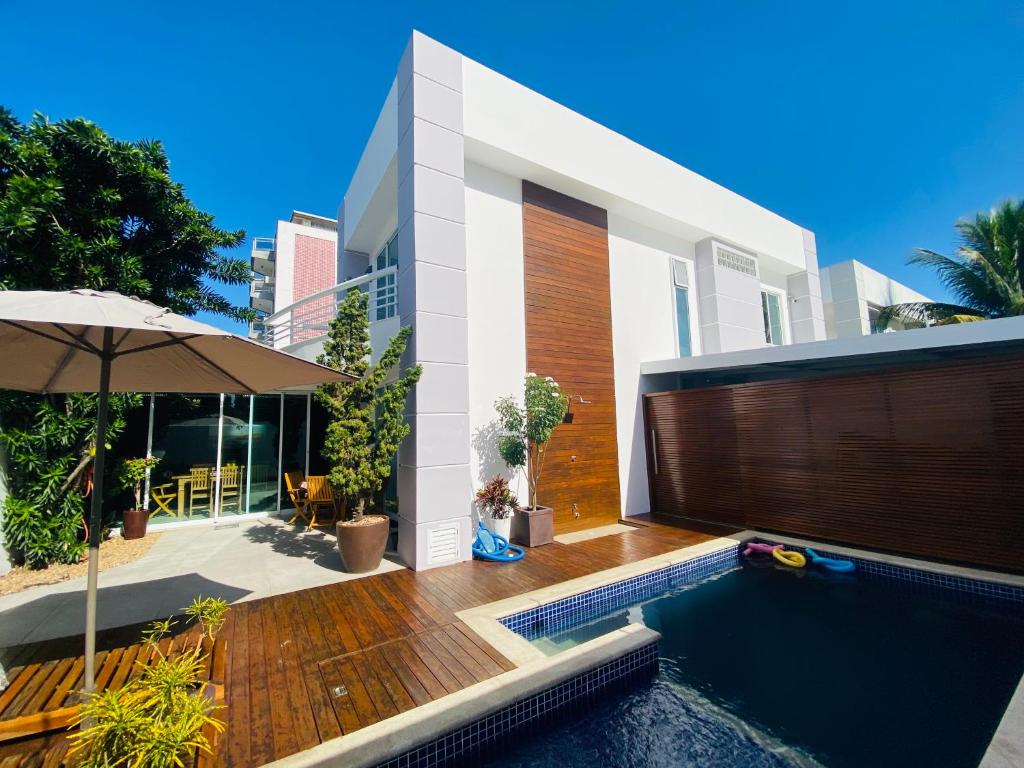 uma casa com piscina e guarda-sol em Cabo Frio FamiliarToca de Gente Feliz em Cabo Frio