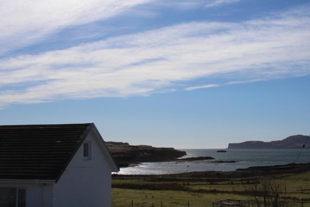 a white house with a view of the ocean at The Loft at Strathardle - Lochside Apartment, Isle of Skye in Dunvegan