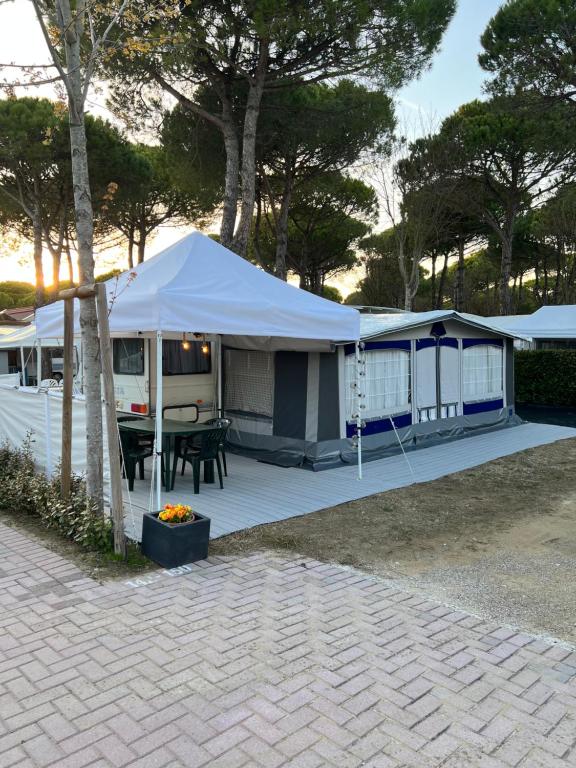 a tent on a patio with a table and a grill at Caravan Cavallino - Valentini in Campeggio Union Lido in Cavallino-Treporti