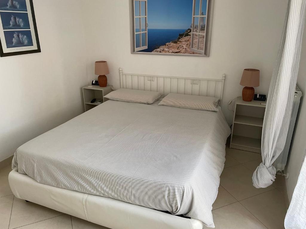 um quarto com uma cama branca e duas mesas de cabeceira em La casa di Murphy em Porto Recanati