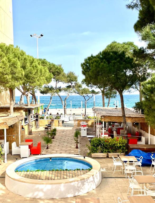 a swimming pool with tables and chairs and the beach at Hotel Serenity Platja d'Aro by Pandora Hoteles in Platja d'Aro