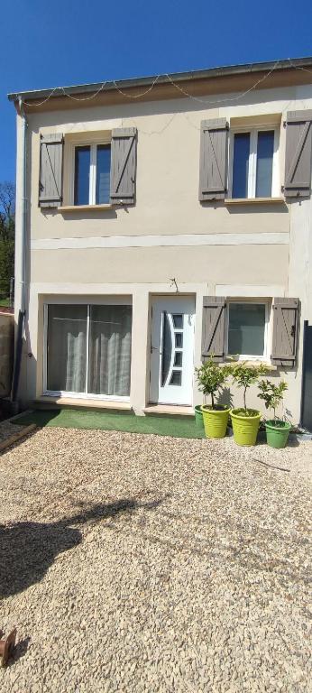 une maison avec deux plantes en pot devant elle dans l'établissement Petite maison sur les traces de Van gogh, à Butry-sur-Oise