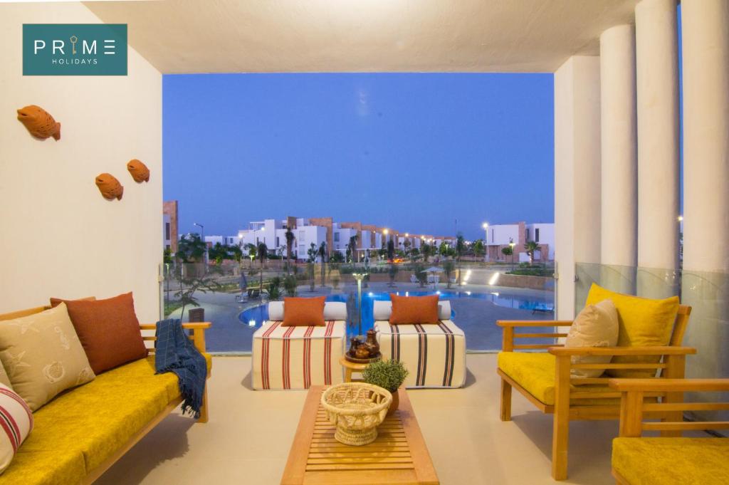 a living room with a yellow couch and a large window at Prime Holidays Seashell in El Alamein