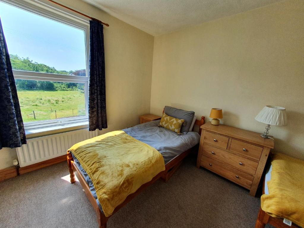 Lake District Holiday Home Ennerdale Sleeps 12 في Cleator: غرفة نوم بسرير ونافذة كبيرة