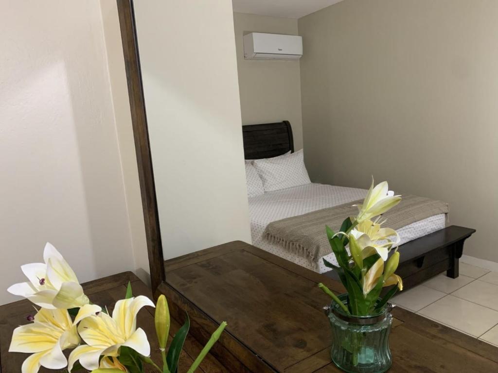 einen Spiegel in einem Zimmer mit einem Bett und Blumen in der Unterkunft Musgrave AnneX- comfy 1 bedroom apartment on the ground floor in Kingston