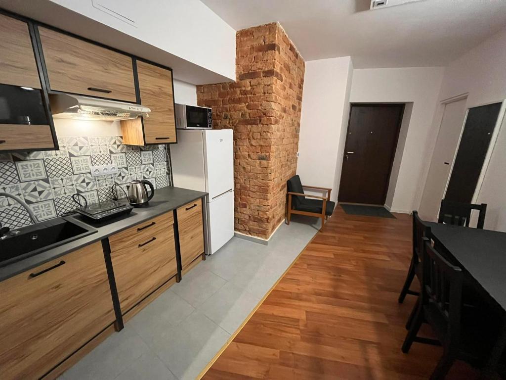 a kitchen with wooden cabinets and a brick wall at Hostel WOKU in Świebodzice
