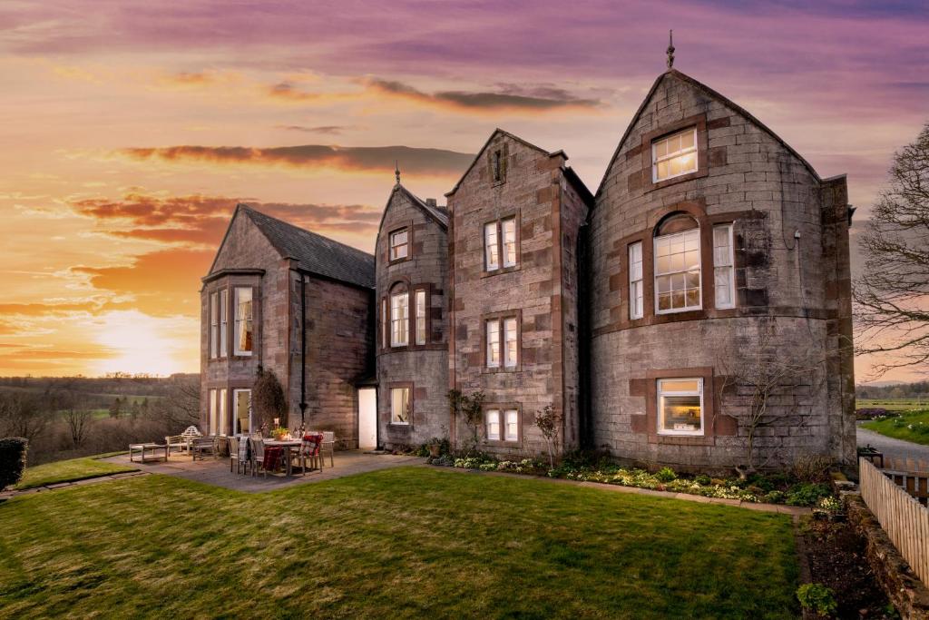 an old stone house with a sunset in the background at Nithbank Country Estate 5 Star GOLD in Thornhill