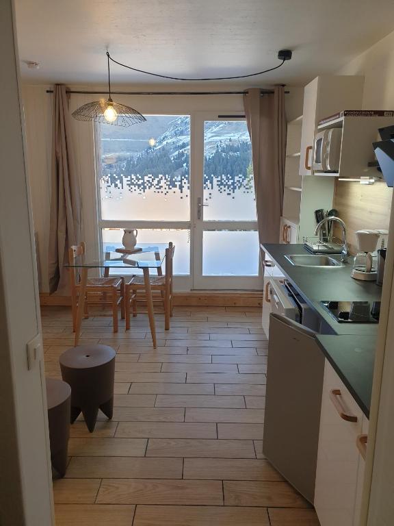 une cuisine et une salle à manger avec une table et une fenêtre dans l'établissement Résidence Alpinéa Mottaret, 3 à 5pers, à Méribel