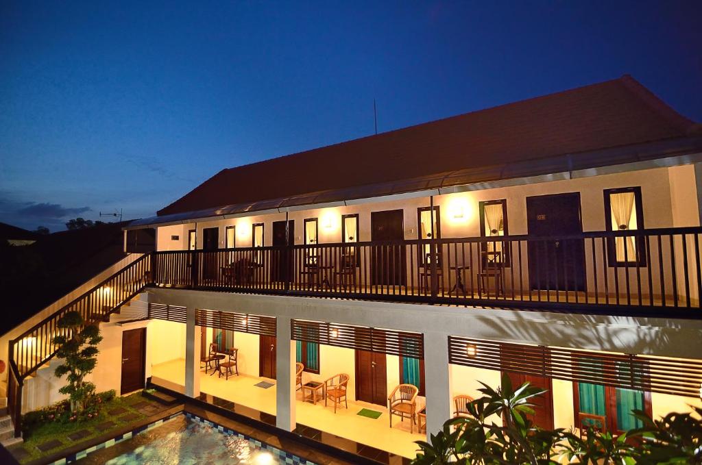 a building with a balcony with a swimming pool at night at Sanur Guest House in Sanur