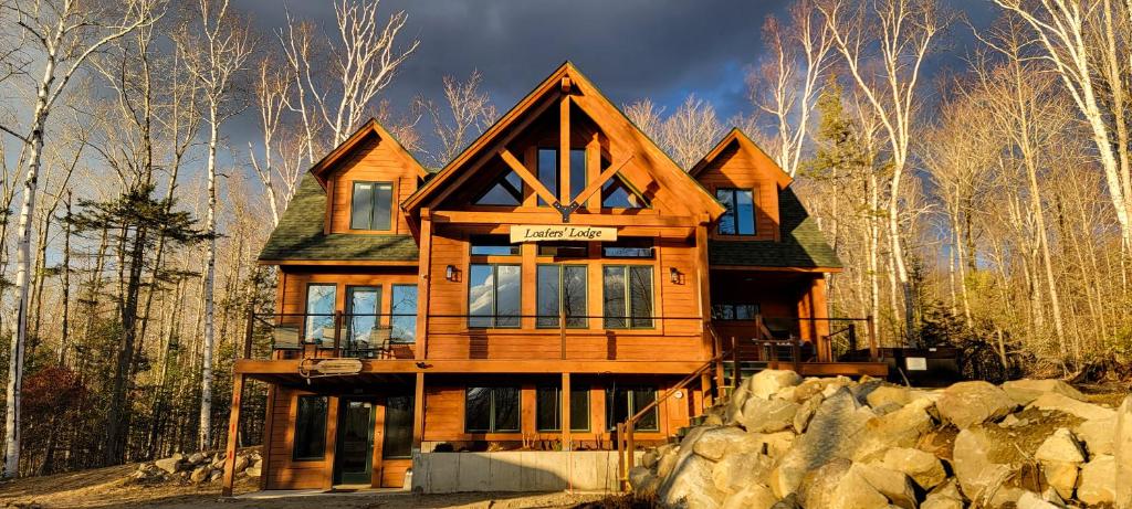 a wooden house in the woods with rocks at Loafers' Lodge in Carrabassett